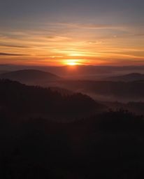 Intense dramatic lighting depicting sunset over misty Tuscan hills, high contrast, creating tension.