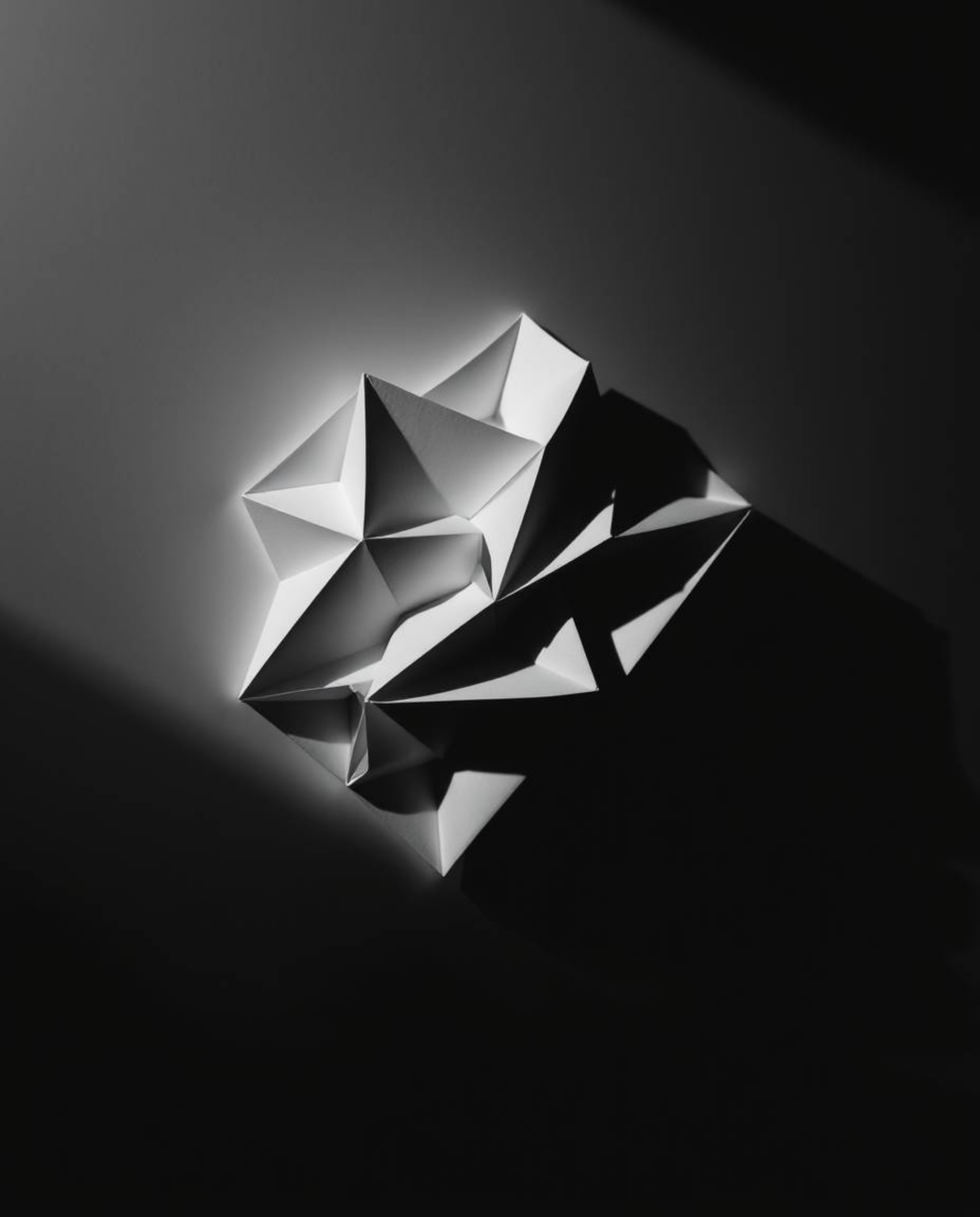 A captivating monochrome image showcases a striking 3D geometric pattern reminiscent of folded paper.  The dramatic chiaroscu
