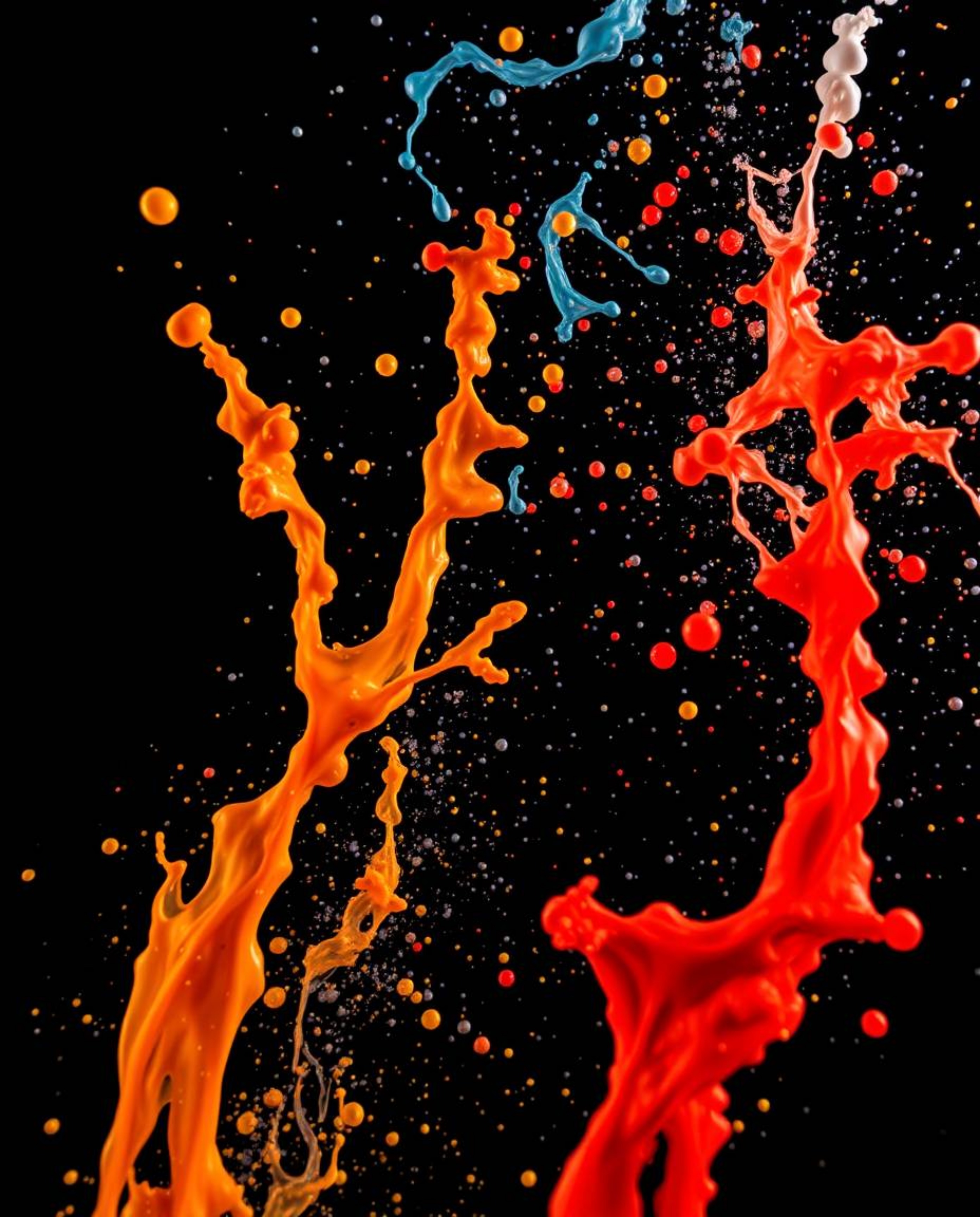 This fine art photograph captures dynamic colorful splashes in a freeze-frame against a stark black background. Shot from a l