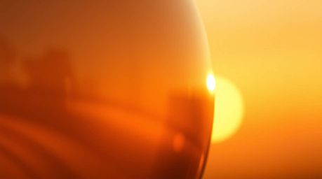 A captivating close-up detail of a glass object, masterfully reflecting smooth gradient textures bathed in the warm, golden h