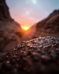 An extreme macro photograph captures a wet, rainy scene of a sunset illuminating sandstone cliffs in a canyon. The lens focus