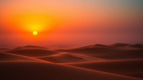 Witness the breathtaking beauty of a high contrast sunset at the edge of a desert, where golden dunes meet deep ultraviolet h
