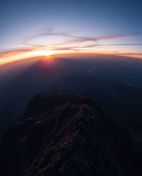 Experience a breathtaking panoramic sunset from a high alpine peak with this stunning overhead bird's eye view. Utilizing lon