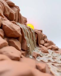 A sculptural clay artwork depicting a dynamic waterfall with a setting sun. The piece features blurred lines and action poses
