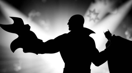 A dramatic close-up image showcasing a silhouetted superhero battling a comical villain in black and white. The photograph em