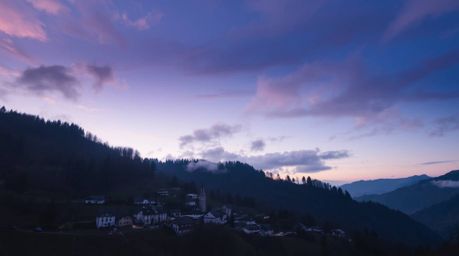 Immerse yourself in the tranquility of a cozy village nestled in a picturesque valley, bathed in the gentle light of a colorf