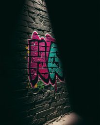 Explore the captivating world of high-contrast, low-key lighting as it illuminates colorful graffiti splashes on a textured b