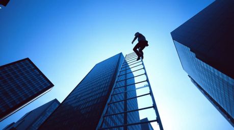 This image depicts an abstract concept of success. A businessperson ascends a transparent ladder vanishing into a vibrant blu