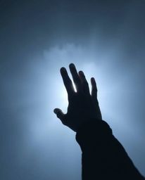 A captivating image portraying a hand reaching towards a source of light emerging from the darkness and thick fog. The low vi