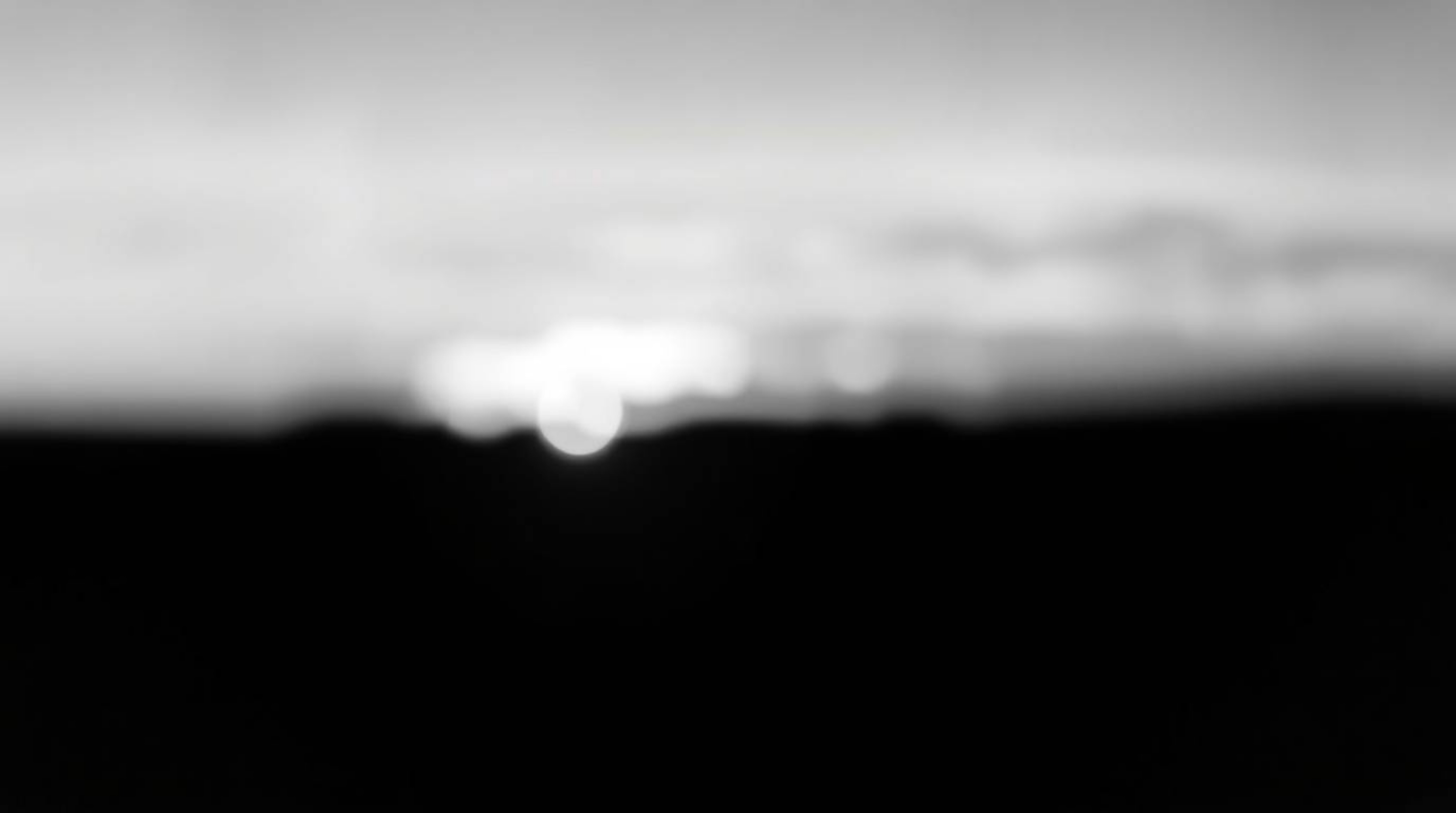 A classic black and white photograph showcasing the ethereal beauty of the Northern Lights emerging over a vibrant sunset.  T