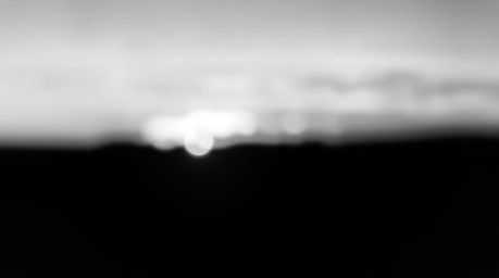 A classic black and white photograph showcasing the ethereal beauty of the Northern Lights emerging over a vibrant sunset.  T