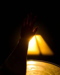 A captivating image depicting a hand reaching towards light emanating from darkness, sculpted with a cast bronze surface and 