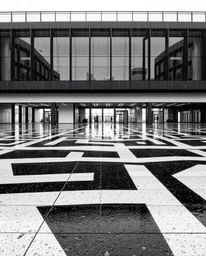 A stunning black and white architectural photograph captures a wet, rainy scene with a captivating geometric optical illusion