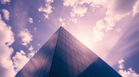 This striking image captures a modern glass building seemingly dissolving into the sky, rendered with strong, harsh light and