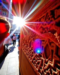 Capture the essence of candid street photography with vibrant reds, oranges, and yellows illuminating intricate Islamic geome