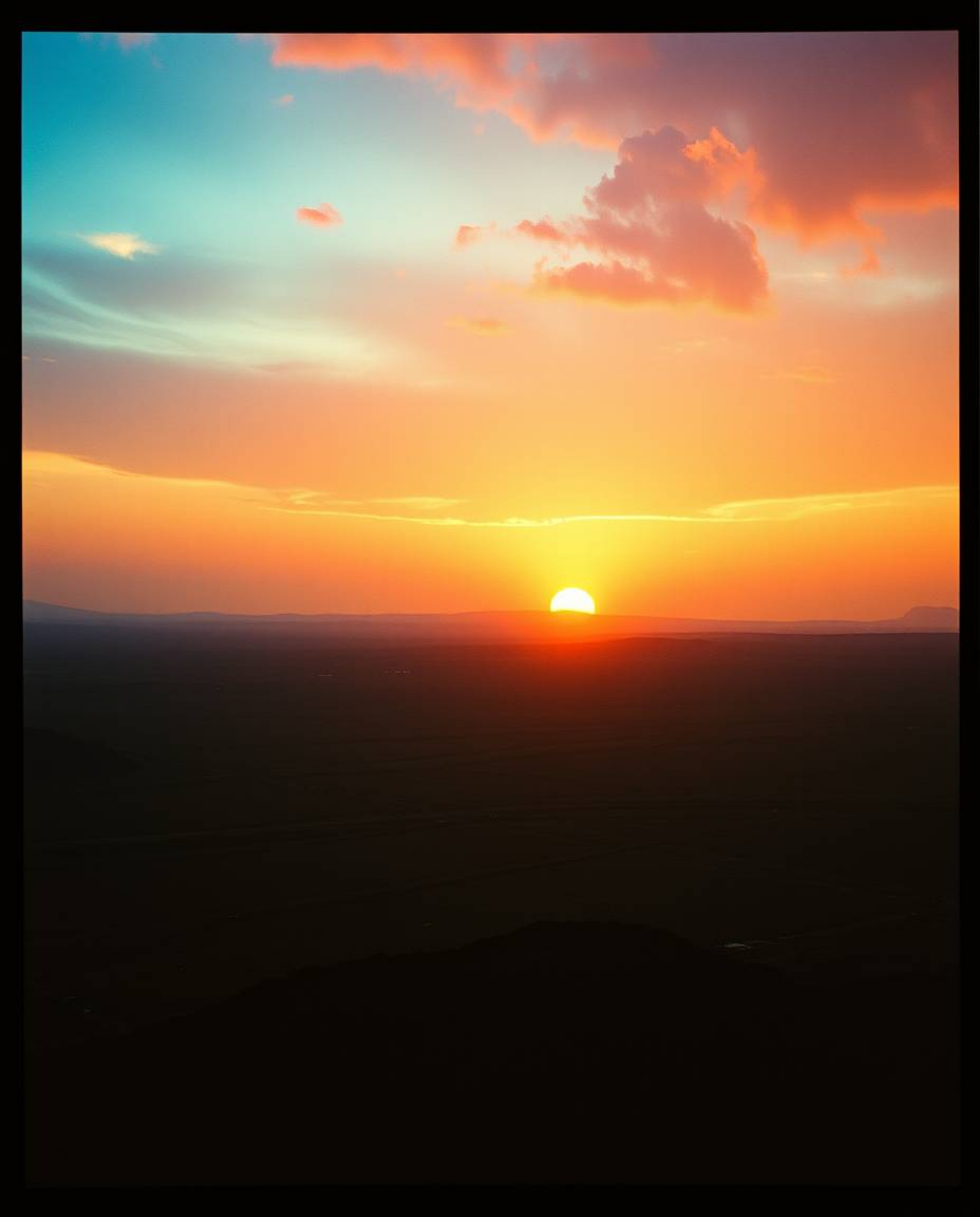 Witness a breathtaking sunrise over a war-torn landscape, bathed in warm terracotta hues and accented by cool teal tones. The