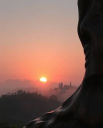 This is a cast bronze sculpture depicting a sunset over the misty, rolling hills of Tuscany. The artwork features an antique 