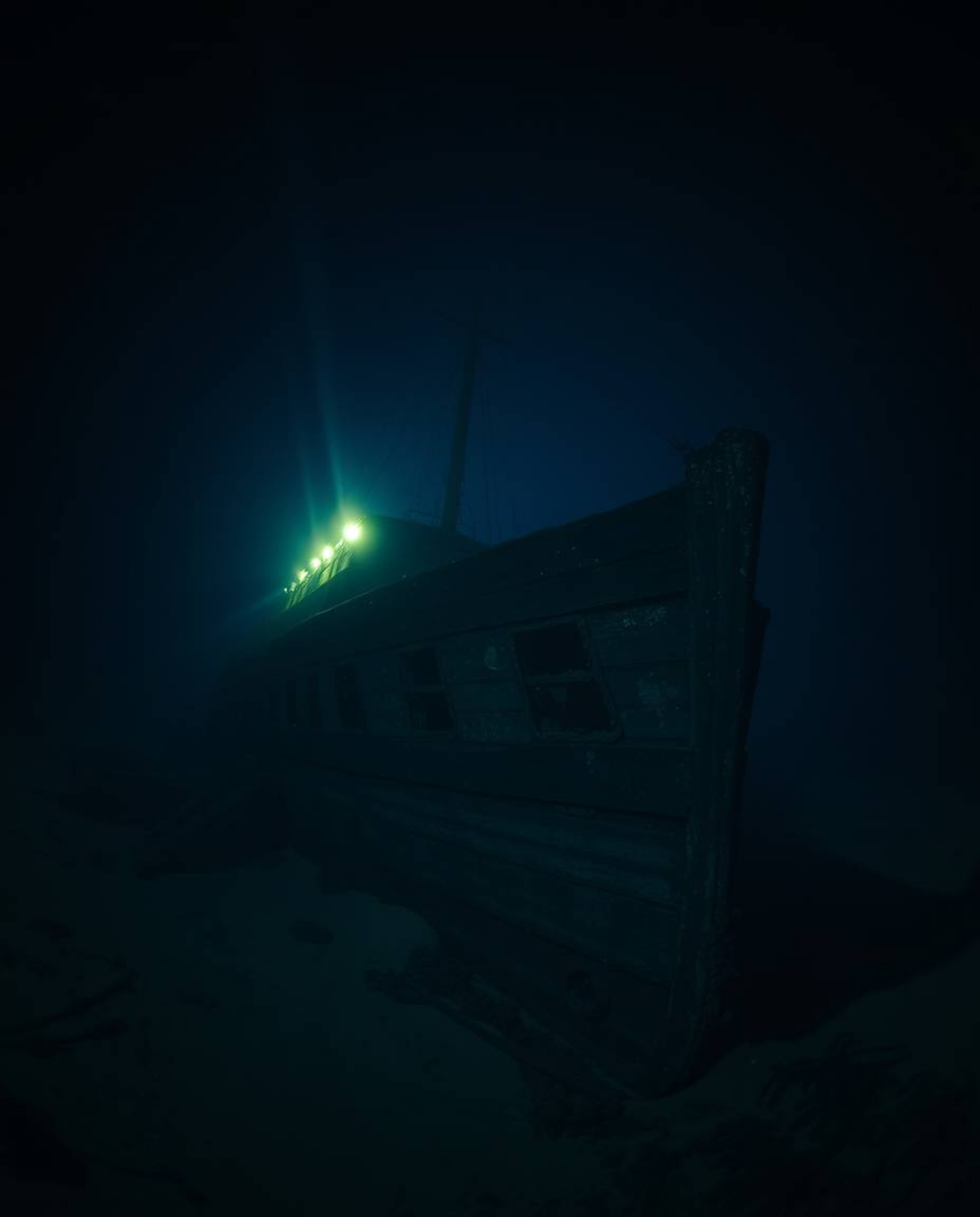 Explore the depths with this captivating high-resolution stock photo of a shipwreck beautifully illuminated deep underwater. 