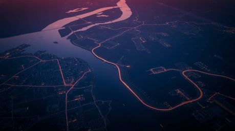 This image depicts a stunning overhead bird's eye view of a river delta illuminated by the vibrant colors of twilight. The st