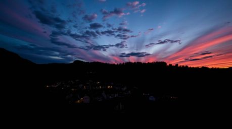 Discover a breathtaking view of a cozy village nestled in a picturesque valley.  The scene is dramatically lit by a vibrant, 