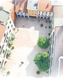 A serene watercolor painting depicts an empty town square from a bird's-eye perspective.  Delicate pastel colors and transluc