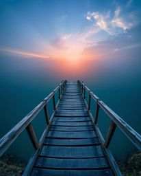 A stunning bird's eye view captures an old wooden bridge stretching over a tranquil river at sunset. The image is defined by 