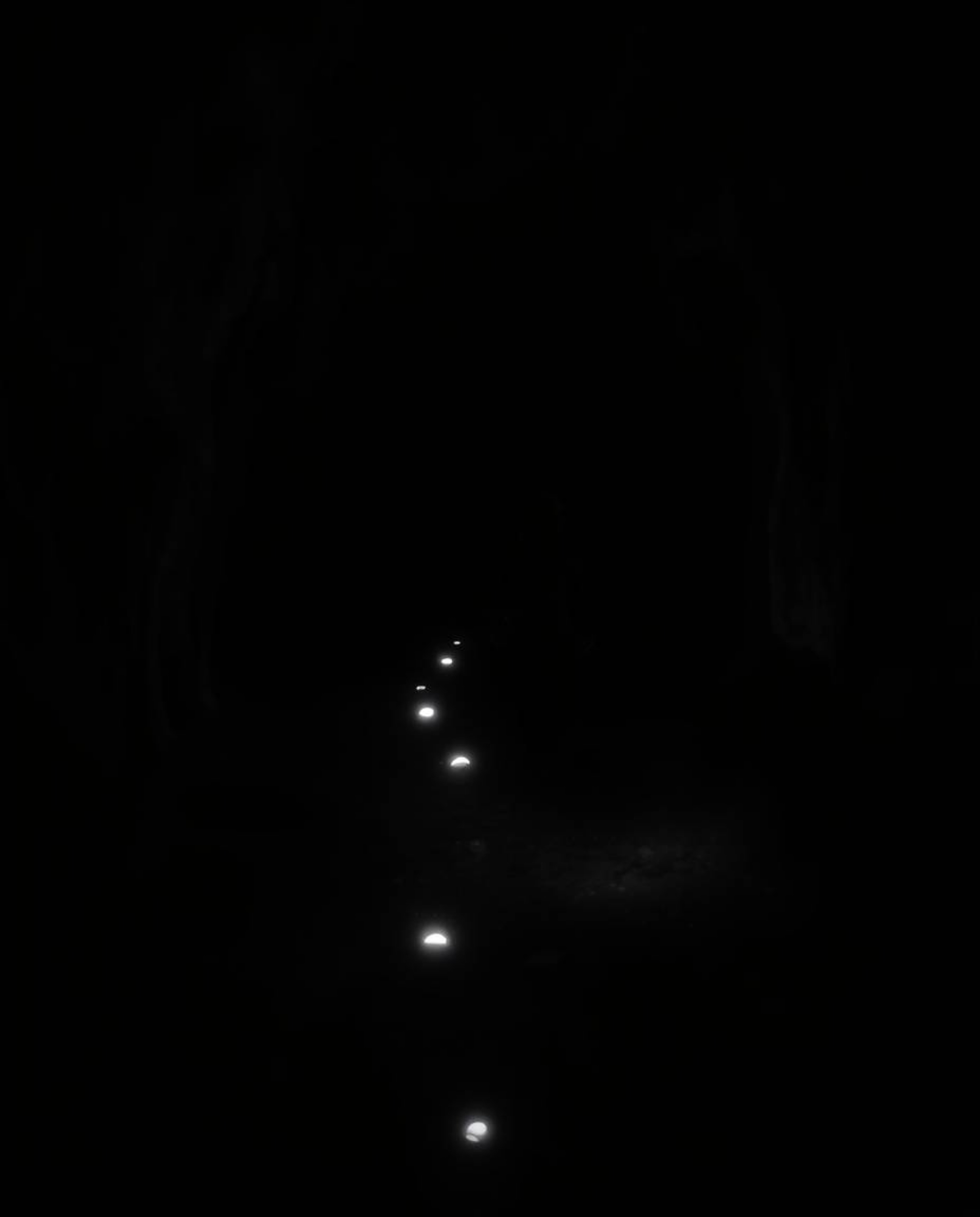 A solitary child, their features obscured by shadow, embarks on a mysterious journey into the depths of a dark cave, guided o