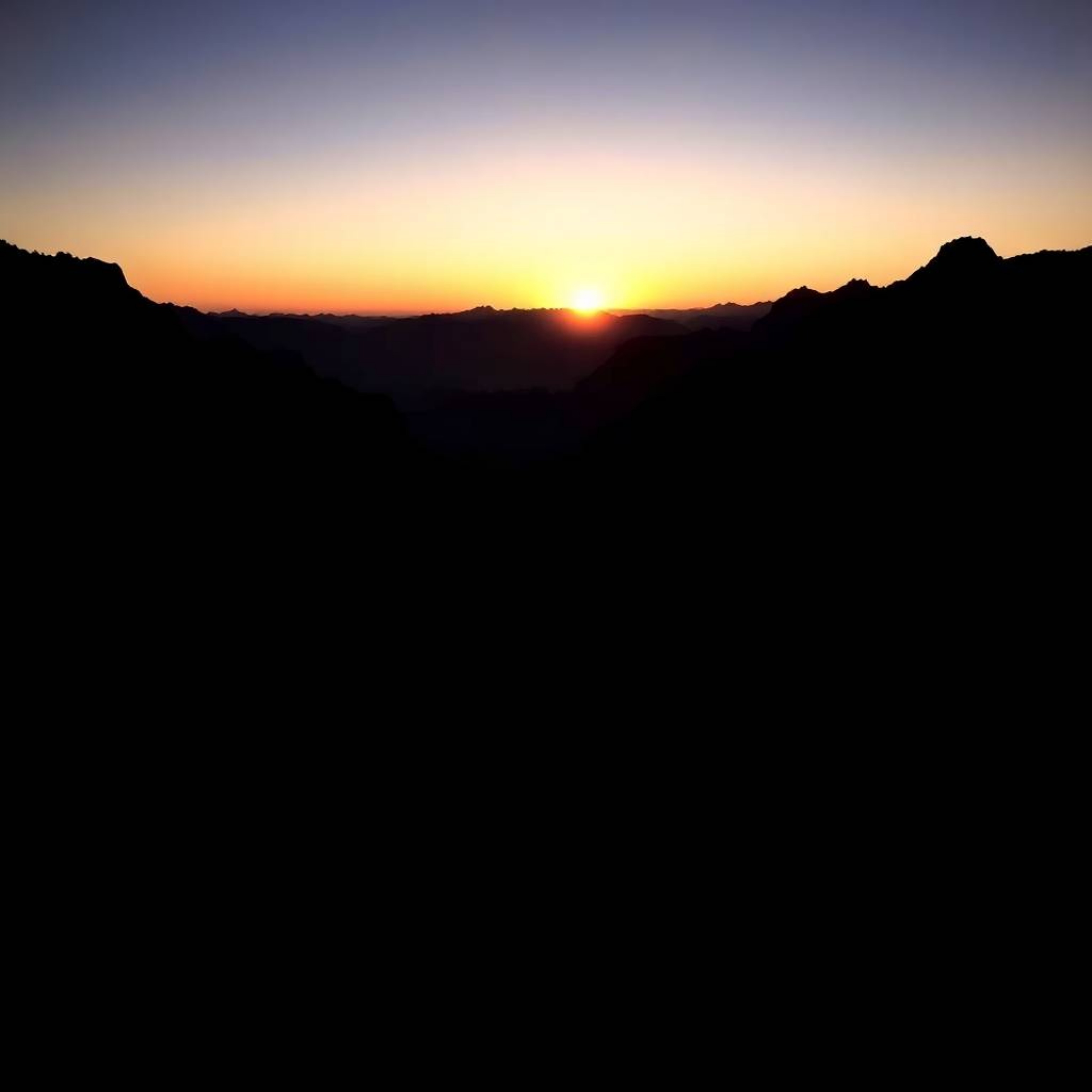 Experience the serene beauty of a jet-black sunset cascading over a tranquil mountain valley.  This image captures the intens