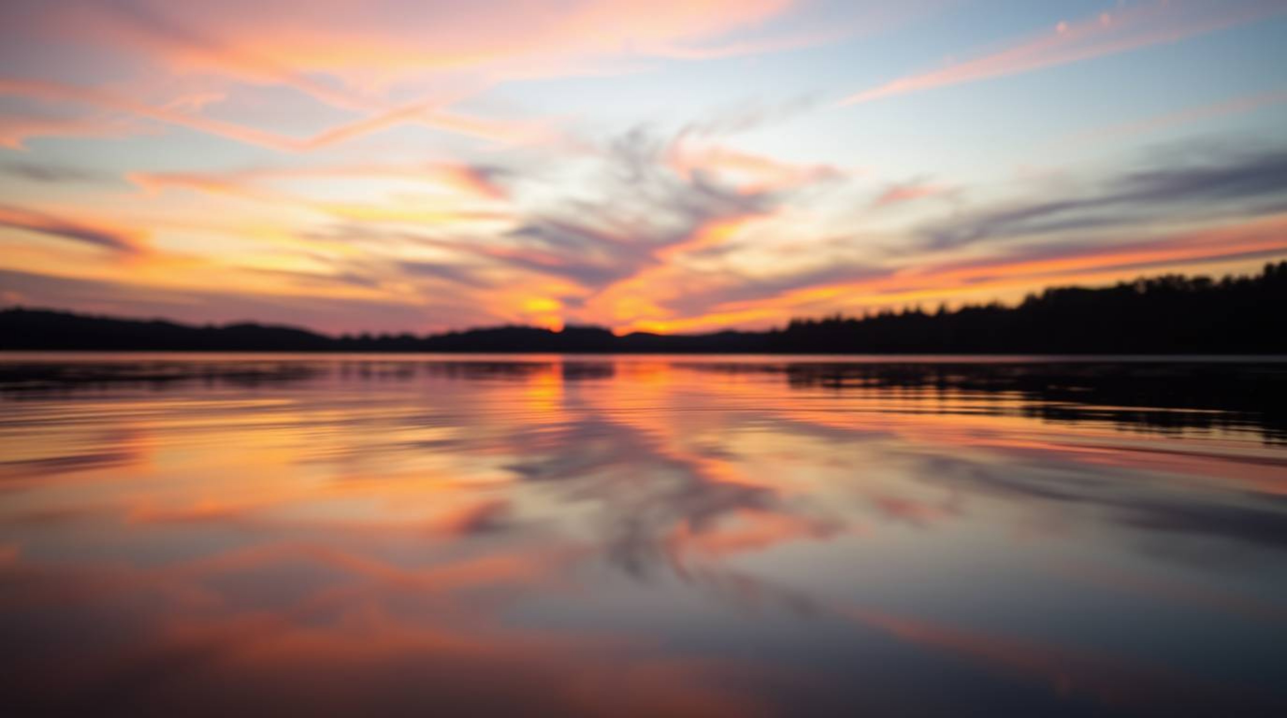 A captivating close-up captures the tranquil beauty of a serene lake mirroring a vibrant sunset sky. The image showcases a sm