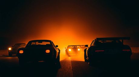 Immerse yourself in a professional fine art photograph capturing a wacky racing scene. Outlandish cars are silhouetted agains