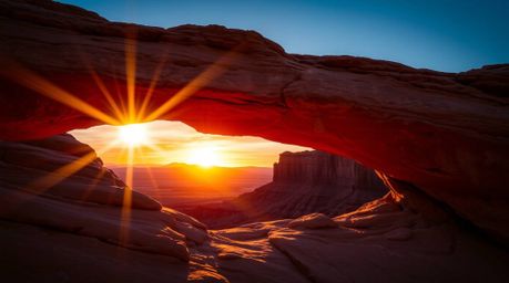 Experience a sophisticated and elegant sunset captured through a natural desert rock arch. The image showcases rich burgundy 