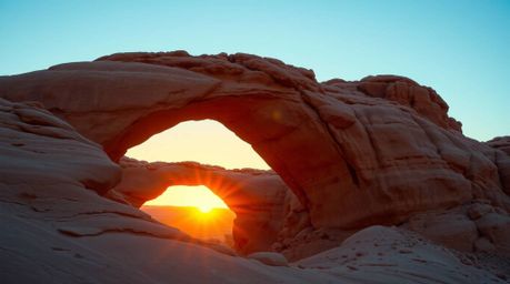 Capture the breathtaking beauty of a desert sunset framed by a natural rock arch with this precise architectural color photog