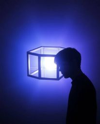 A silhouetted figure is backlit with cool colors, set against a backdrop of repetitive Escher-style impossible cube geometry.