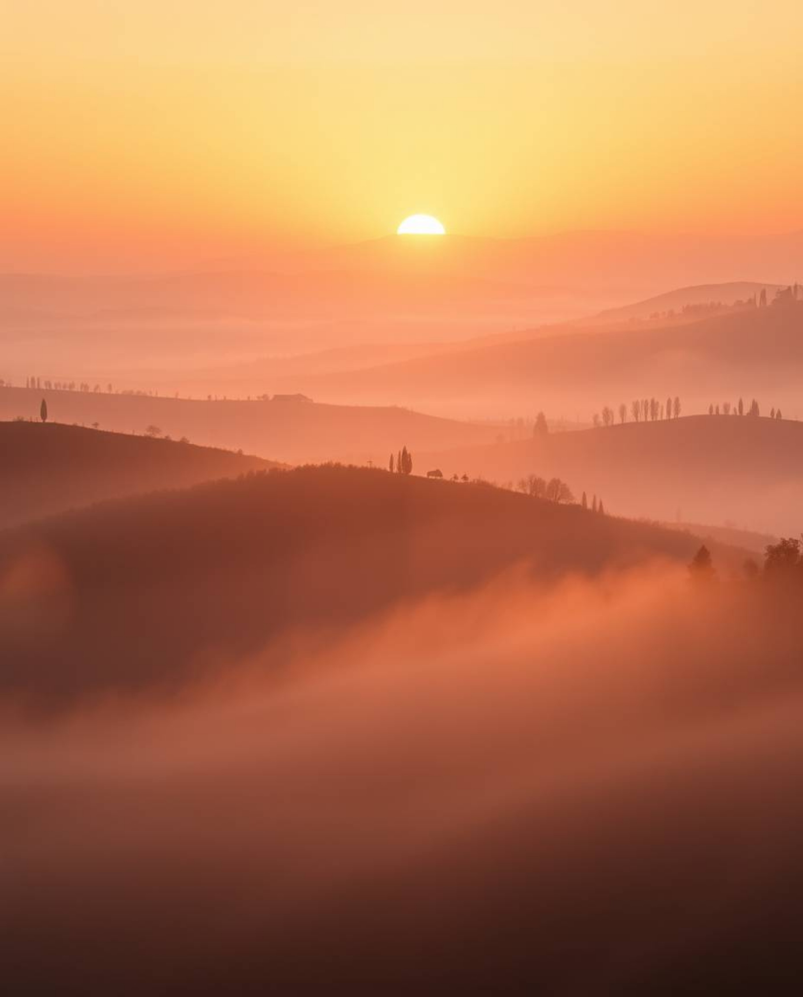 A photograph of a sunset over misty rolling hills in Tuscany, with volumetric lighting creating an ethereal and spiritual vib