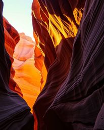 This artwork captures a sunset illuminating sandstone canyon cliffs, defined by its use of strong, hard light. A striking col