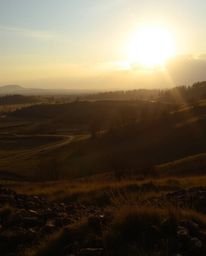 A captivating sunrise illuminates a war-torn landscape, casting strong, hard light that creates dramatic shadows and highligh