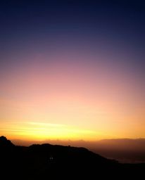 This artwork depicts a sunset sky over a winding coastal highway, enveloped in a soft, dreamy atmosphere. The scene is illumi