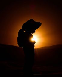 A captivating image of a brave hero embarking on a Disney-style desert adventure.  Silhouetted against a vibrant sunset, the 