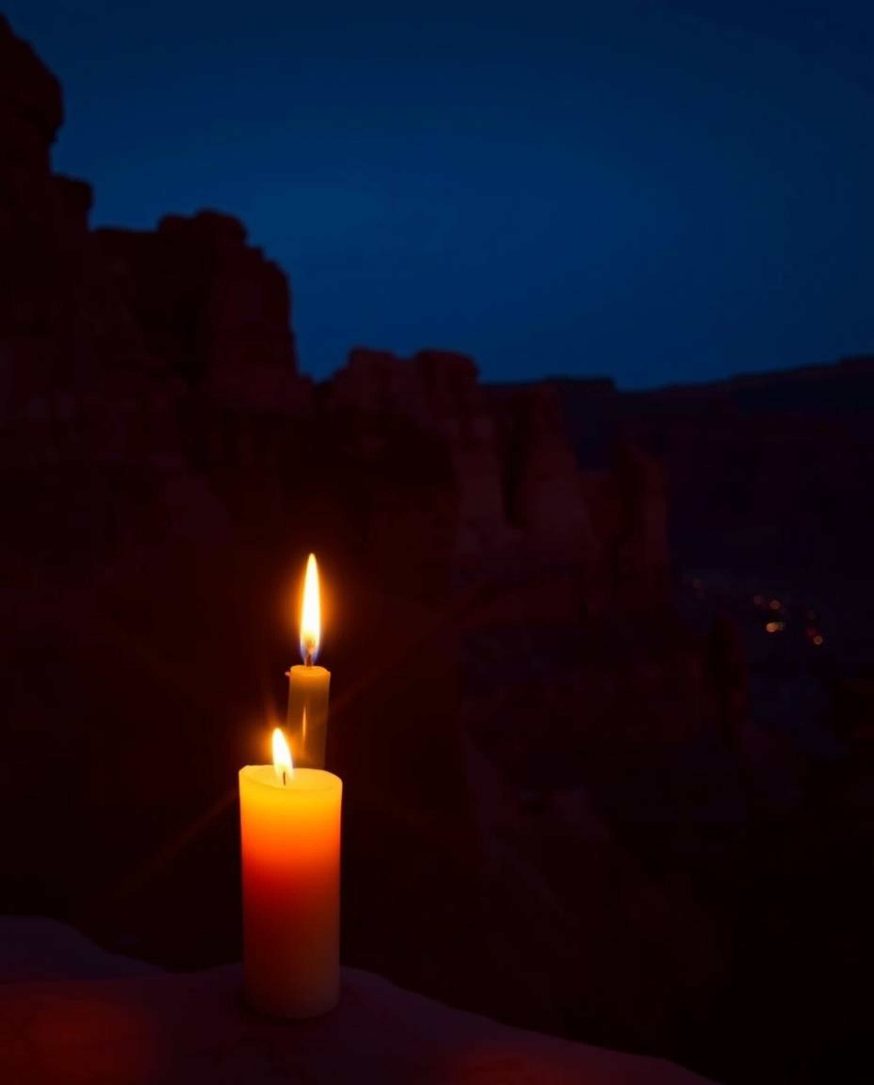 Warm candlelight illuminates sandstone cliffs at sunset, creating a scene with a sophisticated and elegant aesthetic. The lan