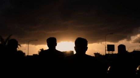 A captivating candid street photograph showcases silhouetted figures against a dramatic backdrop of intensely black thunderst