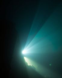 This stunning close-up showcases a shipwreck illuminated deep underwater using volumetric lighting.  Light beams pierce throu