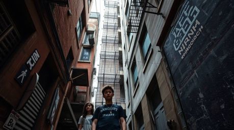 A captivating high-angle photograph showcases a grungy city alley teeming with rebellious teenagers.  The image emphasizes sh