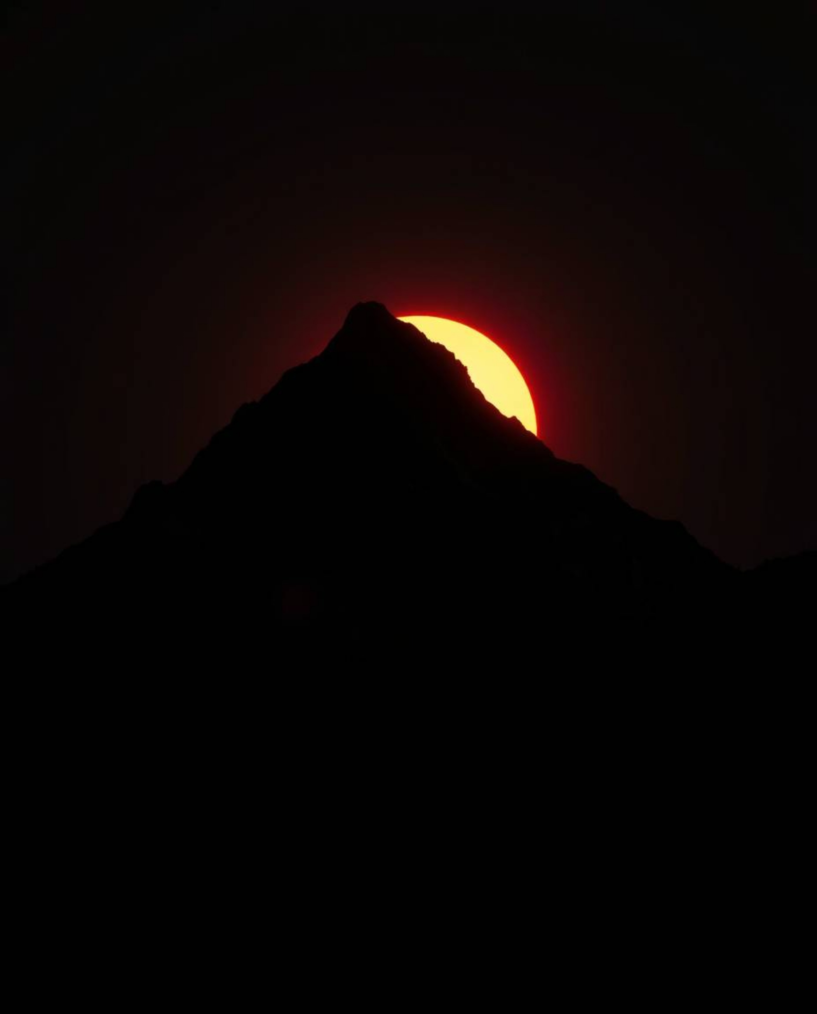 Experience a stark and powerful interpretation of a high alpine peak sunset, rendered almost entirely in intense jet black. T