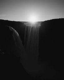 From a high-angle perspective with high contrast and low-key lighting, this image captures a sun setting behind a dramatic wa