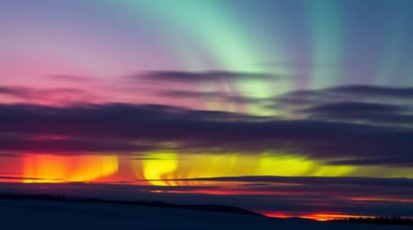 Witness the breathtaking fusion of vibrant, electric colors as the Northern Lights begin their dance across the twilight canv