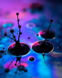 Explore the mesmerizing world of dark-toned ink splashes in water, brought to life with iridescent colors and captured in stu