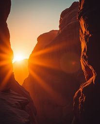 This image captures a sunset illuminating sandstone cliffs in a canyon, presented in a dramatic cinematic style. A warm golde
