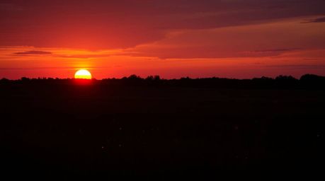 Experience the magic of a warm sunset painting the sky over a tranquil meadow.  Deep shadows contrast with vibrant reds, oran