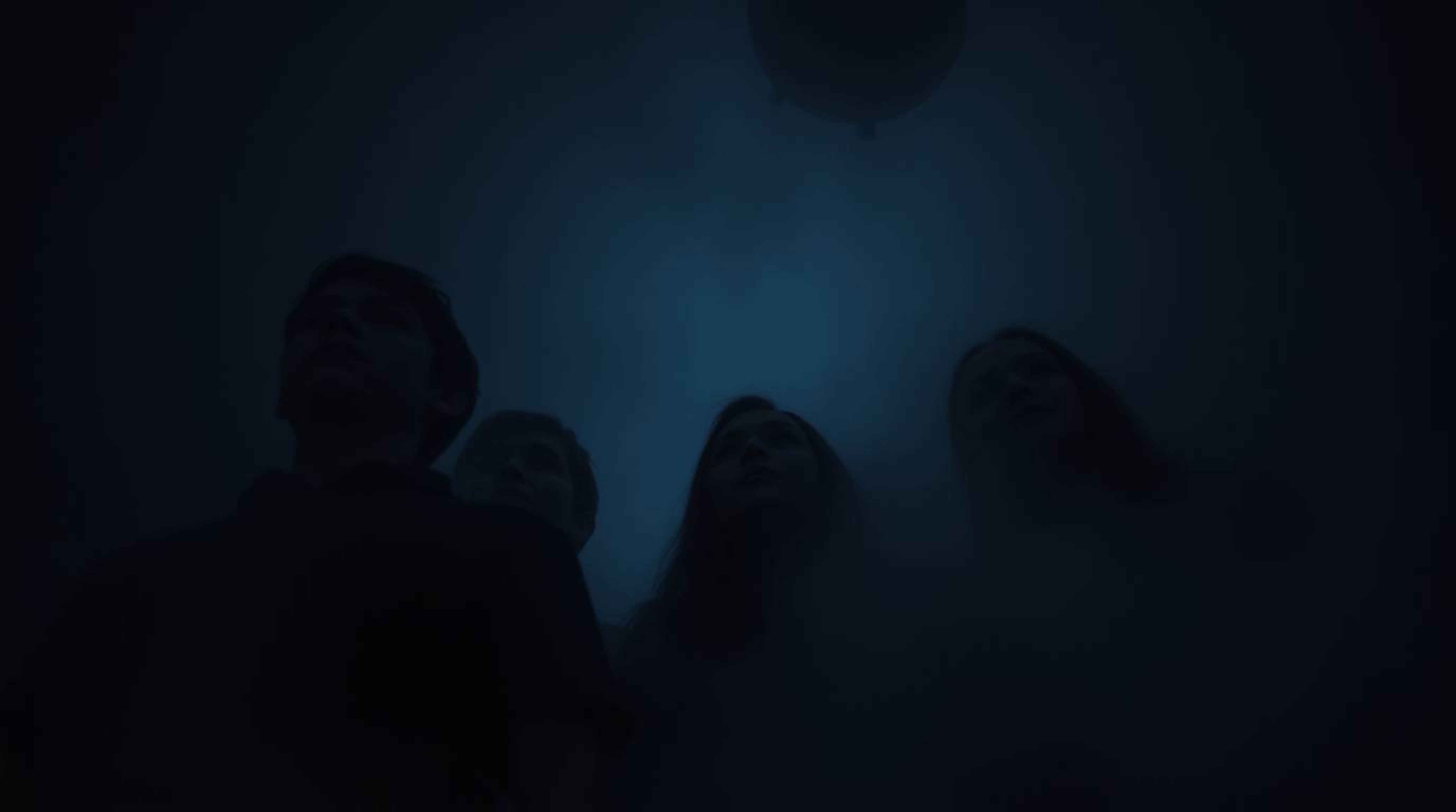 A group of teenagers bravely unravels a chilling mystery within a dimly lit, haunted mansion.  Thick fog obscures their faces