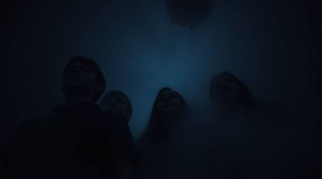 A group of teenagers bravely unravels a chilling mystery within a dimly lit, haunted mansion.  Thick fog obscures their faces